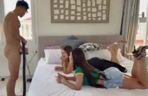 Dos maduras en la cama de un dormitorio, una con top negro y otra con camiseta verde de Brasil, junto a un chico de la limpieza